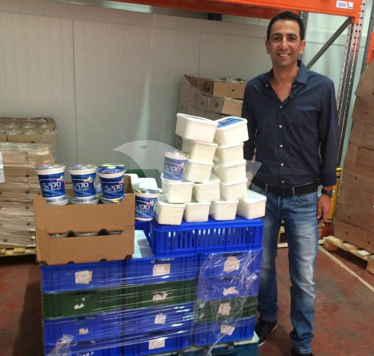 Shai Davaroff posing with donated Strauss dairy products in honor of Shavuot food drive