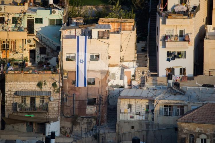 An Israeli flag hangs on a building in east Jerusalem neighborhood of Silwan